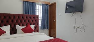 een slaapkamer met een bed met rode kussens en een flatscreen-tv bij NMS GRAND VIEW TOWER in Pondicherry