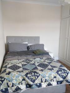 Una cama con edredón en un dormitorio en Whites Place, en Slades Green