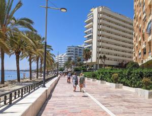 people walking down a sidewalk next to the beach at Marbella Old Town Apartments by Homing in Marbella