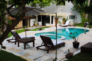 a patio with chairs and an umbrella next to a pool at Villa Maria Bonita in Pipa