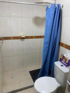 baño con aseo y cortina de ducha azul en Casa Mobiliada em Arraial (20 metros do CÁS, onde saem os passeios de barco), en Arraial do Cabo