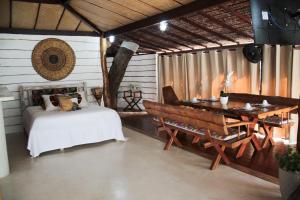 a bedroom with a bed and a table and a bench at Villa Maria Bonita in Pipa