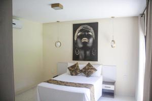 a bedroom with a bed with a painting on the wall at Villa Maria Bonita in Pipa
