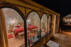 Desert Luxury Camp Experience في مرزوقة: غرفة نوم بسريرين في غرفة مقوس