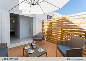 a patio with chairs and a table and an umbrella at Apartamentos La BRUJULA by CadizRentals in Cádiz