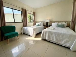 a bedroom with two beds and a green chair at Paradise Surf Hotel in San Miguel