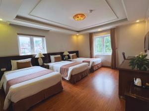 two beds in a hotel room with two windows at Sapa Adam Hotel in Lao Cai