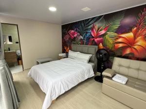 um quarto com uma cama grande e um mural de flores em SIETE COLORES em Chachagüí
