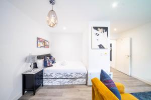 a bedroom with a bed and a yellow couch at Prime Serviced Apartments Sheffield Center in Sheffield