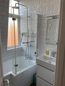 a white bathroom with a shower and a sink at Beautiful 3 Bed in Leafy Hampstead in London
