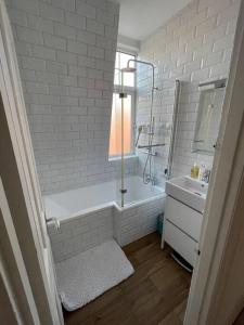 a white bathroom with a tub and a sink at Beautiful 3 Bed in Leafy Hampstead in London