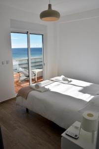 een slaapkamer met een bed met uitzicht op de oceaan bij Over the Beach in Monte Gordo
