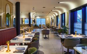 a restaurant with tables and chairs and windows at Courtyard by Marriott London Heathrow Airport in Hayes