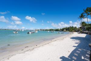 a beach with boats in the water and palm trees at THE BAY 3 ***** in Grand Baie