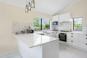 uma cozinha branca com armários e electrodomésticos brancos em Meadowview Retreat is only 5 mins to beach em Waiau Pa
