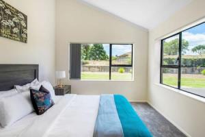 um quarto branco com uma cama grande e 2 janelas em Meadowview Retreat is only 5 mins to beach em Waiau Pa