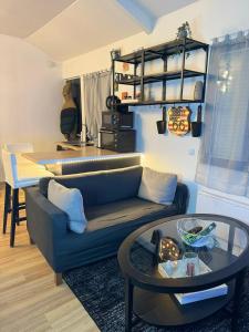 ein Wohnzimmer mit einem blauen Sofa und einem Tisch in der Unterkunft Maisonnette proche de Paris & Home cinema in Bourg-la-Reine
