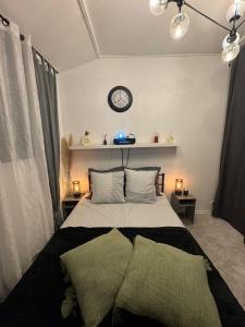 ein Schlafzimmer mit einem Bett mit zwei Kissen und einer Uhr in der Unterkunft Maisonnette proche de Paris & Home cinema in Bourg-la-Reine