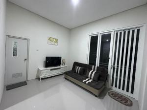 uma sala de estar com um sofá e uma televisão em Villa Sunrise F1 em Malang