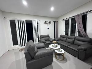 uma sala de estar com um sofá, cadeiras e uma mesa em Villa Sunrise F1 em Malang