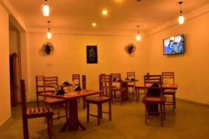 Lily Resort Udawalawe في اوداوالاوي: غرفة طعام مع طاولات وكراسي خشبية