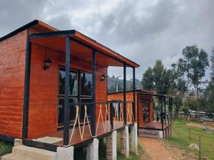 Casa de madera con ventanas de cristal en un campo en Hospedaje cabaña Guatavita Finca las Acacias en Guatavita