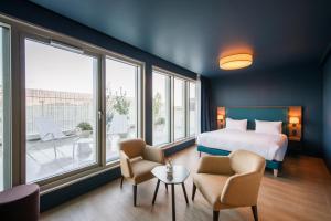 a bedroom with a bed and chairs and windows at Hôtel de la Cité in Nantes