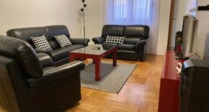 Sala de estar con 2 sofás de cuero y mesa de centro en Red Carpet Podgorica, en Podgorica