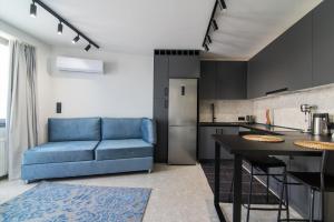 uma sala de estar com um sofá azul e uma cozinha em Kolonaki Square Central Penthouse em Atenas