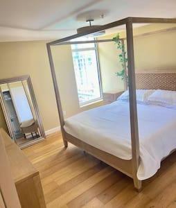 a bedroom with a canopy bed and a mirror at Luxe 1BR plus Den near Little Italy Gem in San Diego