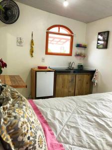 a bedroom with a kitchen with a sink and a bed at Suíte Colorida em Cabo Frio in Cabo Frio