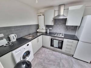 uma cozinha branca com uma máquina de lavar roupa e um lavatório em Peaceful 4 Bedroom House with Free Parking em Liverpool