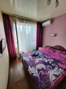 1 dormitorio con 1 cama con edredón morado y blanco en Квартира возле Радмир ул.Чернивецкая 5в, en Járkov