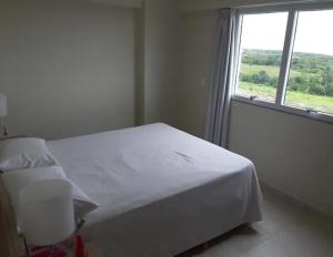 a white bed in a room with a window at SALINAS PARCK in Salinópolis