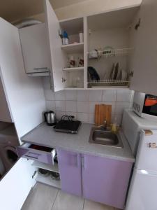 una pequeña cocina con armarios blancos y fregadero en Квартира возле Радмир ул.Чернивецкая 5в, en Járkov