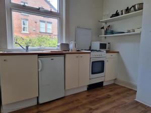 een keuken met een wastafel, een fornuis en een raam bij Blue Door Cottage in Meanwood