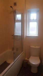 a bathroom with a toilet and a shower and a window at Blue Door Cottage in Meanwood