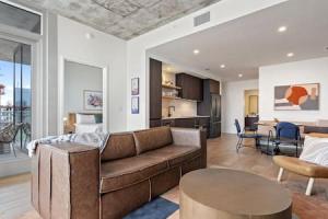 a living room with a brown couch and a kitchen at 2BR Lux Highrise + Austin + Vibrant Rainey St in Austin