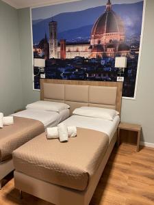 two beds in a room with a picture of a city at Titta & Ruffo in Pisa