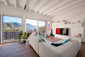 un soggiorno con divano bianco e TV di Elegant Lugano Lake View - Happy Rentals a Caslano