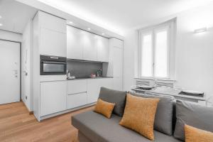 a living room with a gray couch and a kitchen at Sebenico 10 in Milan