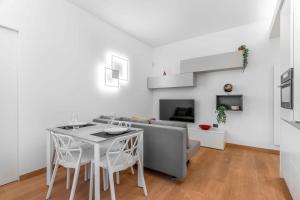 een witte woonkamer met een tafel en een bank bij Sebenico 10 in Milaan
