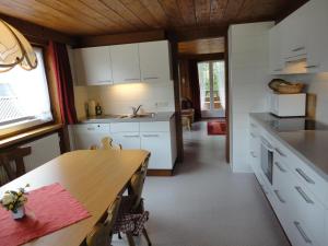 cocina con armarios blancos y mesa de madera en Haus Mellenbach, en Mellau