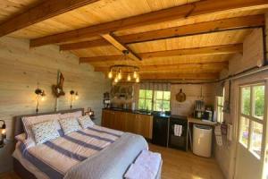 a bedroom with a bed and a kitchen in a cabin at Driftwood Retreat with Hot tub in Week Saint Mary