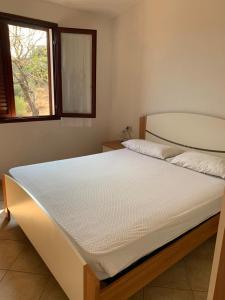 um quarto com uma cama branca e uma janela em Residence Mare Sol Appartamento in affitto Budoni em Porto Ottiolu