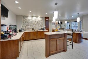 a large kitchen with wooden cabinets and a stone wall at Staybridge Suites - San Antonio - Schertz, an IHG Hotel in Schertz
