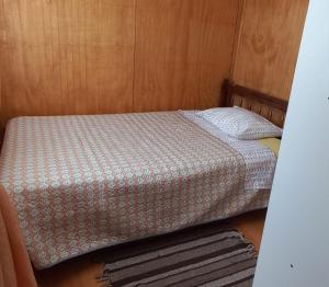 a small bed in a room with a wooden wall at Cabañas Cadiz Valdivia in Valdivia