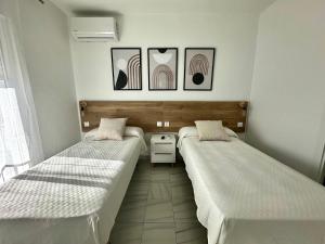 a room with two beds and a table and pictures at Hostal Merino Jédula in Jedula