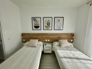 two beds in a room with pictures on the wall at Hostal Merino Jédula in Jedula