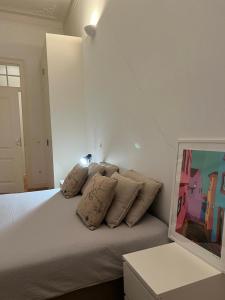 ein Schlafzimmer mit einem weißen Bett mit Kissen darauf in der Unterkunft Quarto no Chiado centro de Lisboa in Lissabon